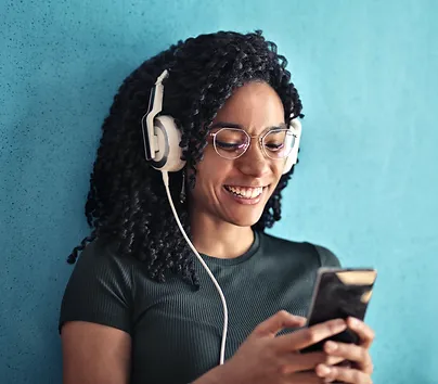 Young woman smiling, listening to music device using headphones